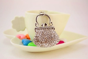 Detail showing handbag shaped rhinestone keychain hanging on a porcelain cup
