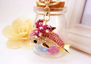 Close-up of dolphin keychain with pink rhinestones and a bow on a golden keyring