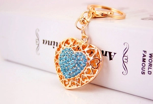 Detail of a heart keychain with sky blue rhinestones and gold hollow metal patterns