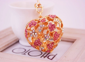 Détail du porte-clés en forme de cœur évidé avec strass roses et breloques lune étoile