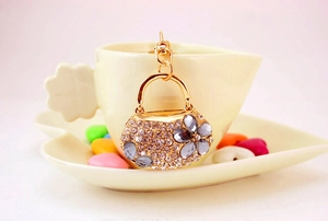 Detailed macro of a crystal handbag keychain on a coffee cup with floral rhinestone patterns