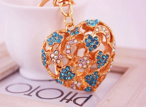 Gros plan d'un porte-clés coeur doré avec strass bleus et motifs étoile lune