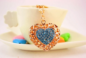 Detailed macro view of heart-shaped keychain with blue rhinestones on a gold metal frame