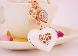 Close-up of rose gold heart keychain with enamel leopard print and crystals on a white cup