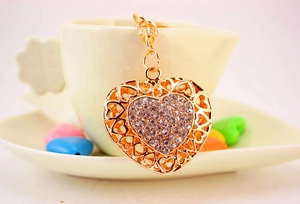 Close-up of golden hollow heart keychain with sparkling rhinestones on ceramic