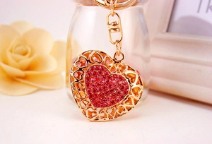 Detailed view of heart-shaped keychain with pink rhinestones and golden metal finish