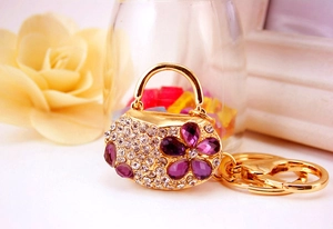 Macro detail of handbag keychain featuring purple crystal flower and gold plating