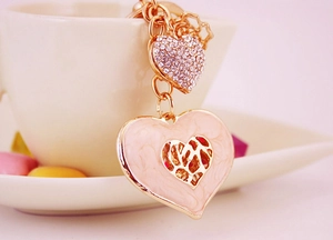 Close-up of pink enamel heart keychain with rhinestones and gold hollow metal texture
