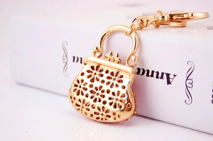 Detail view of golden purse keychain featuring hollow flower patterns and pink rhinestones
