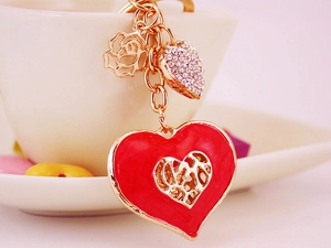 Detail of red hollow heart keychain with sparkling rhinestones on a white ceramic cup