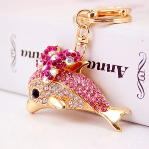 Cute dolphin keychain with pink rhinestones and a bow on a golden metal key ring