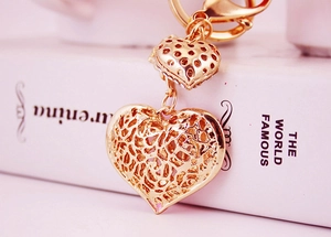 Close-up of golden hollow heart keychain with rhinestone inlay on white book
