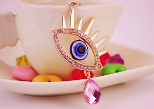 Vue macro d'un pendentif œil maléfique avec cristal goutte rose sur une tasse