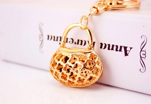 Detail of a golden handbag keychain with hollow clover pattern on a book cover