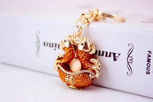 Detail of golden double koi fish keychain with red enamel and lucky fortune bowl charm