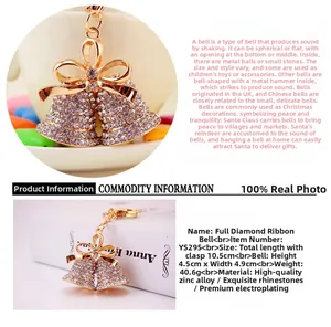 Detail view of a crystal-studded Christmas bell keychain with a gold ribbon bow accessory