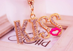 Detail shot of sparkling rhinestone KISS letters with a vibrant hot pink lip pendant charm