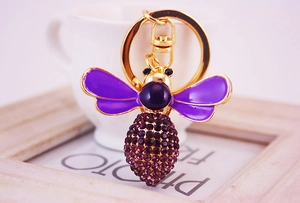 Macro detail of bee keychain with purple enamel wings and sparkling rhinestones