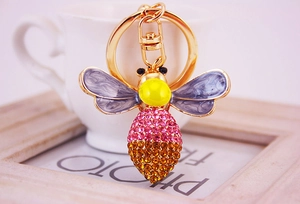 Close-up of a gold bee keychain with pink rhinestones and purple enamel wings