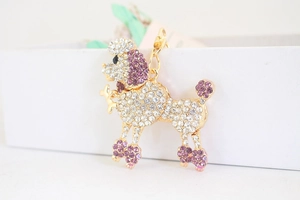 Gros plan d'un porte-clés caniche avec strass violets et blancs et fermoir mousqueton doré
