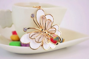 Macro shot of gold butterfly charm with white enamel wings and sparkling rhinestones