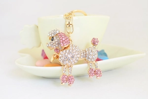 Vue détaillée d'un porte-clés caniche doré avec des strass roses et blancs sur un plat