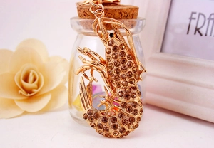 Detail of golden lobster keychain with amber rhinestones on a decorative glass bottle