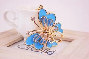 Detail of blue enamel butterfly keychain with white rhinestones on a ceramic background