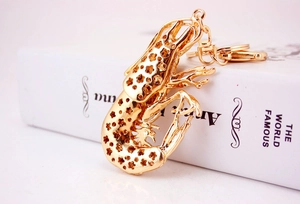 Detail of golden lobster keychain featuring star cutouts on a vintage book background