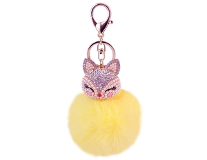 Detail of fox head keychain with purple rhinestones and large yellow faux fur pompom