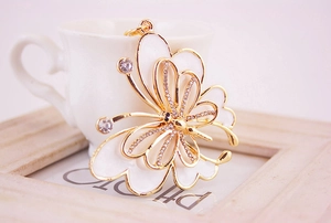 Detail of elegant butterfly keychain with gold metal frame and white enamel inlay