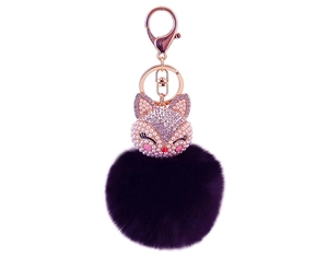 Close-up of fox keychain with purple faux fur pompom and rose gold lobster clasp
