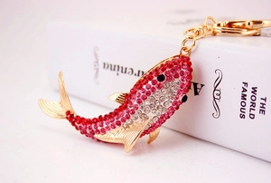 Close-up of a shark keychain with sparkling red and white rhinestones and a gold lobster clasp