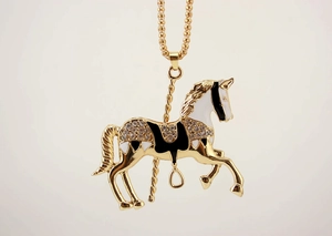 Detail of a golden carousel horse pendant with enamel finish and sparkling crystals