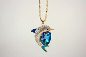 Detailed close-up of a golden dolphin pendant with blue crystals and enamel inlay