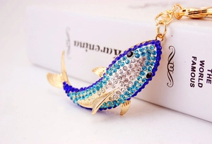 Macro detail of a golden shark keychain with blue and white rhinestones on a book