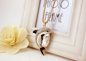 Detailed shot of golden dolphin pendant with sparkling crystals on a Chopin chain