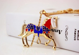 Macro detail of carousel pendant necklace with blue crystals and red enamel finish