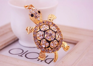 Gros plan d'un porte-clés tortue dorée avec strass scintillants et émail noir