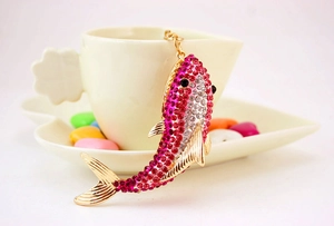 Macro shot of a pink crystal-encrusted shark keychain hanging on a white coffee cup