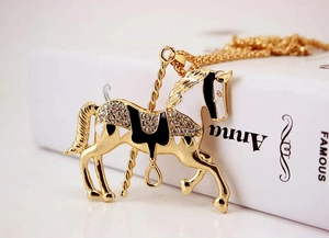 Close-up of golden carousel horse pendant with white enamel and sparkling rhinestones
