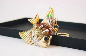 Détail d'un porte-clés poisson tropical en métal doré avec strass colorés et émail brillant