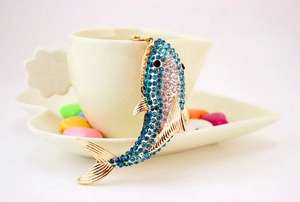 Detailed close-up of a sparkling shark keychain decorated with blue rhinestones on a cup