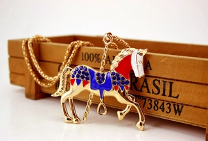 Close-up of golden carousel necklace with red and blue enamel and sparkling rhinestones