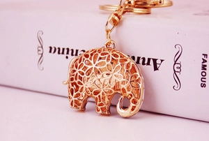 Détail d'un porte-clés éléphant doré avec des motifs floraux évidés et une chaîne en métal