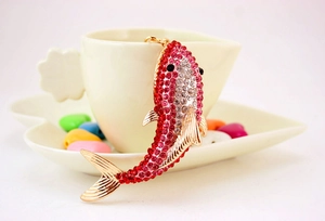 Detail of shark keychain featuring pink rhinestones and a gold-tone finish on a ceramic cup