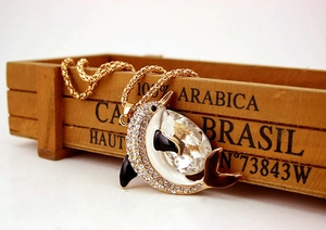 Detail of golden dolphin pendant with sparkling crystal and rhinestones on a rustic base