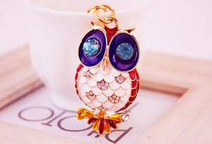 Détail macro du porte-clés hibou avec yeux en strass bleus et finition en émail coloré