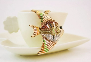Détail d'un porte-clés poisson tropical en cristal accroché à une tasse en céramique