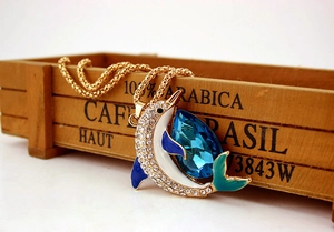 Detail of golden dolphin pendant necklace with blue crystal and colorful enamel inlay